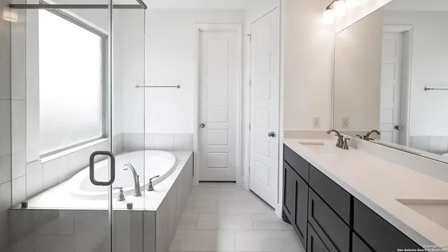 a bathroom with a double vanity sink a mirror and a bathtub