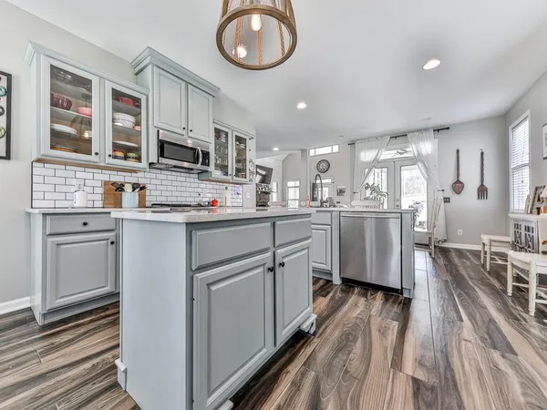 a kitchen with stainless steel appliances granite countertop a sink a stove top oven a chimney cabinets and wooden floor