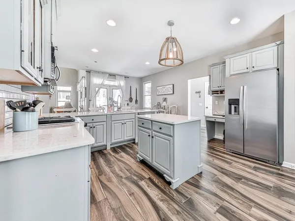 a kitchen with stainless steel appliances a sink a stove a refrigerator cabinets and a window