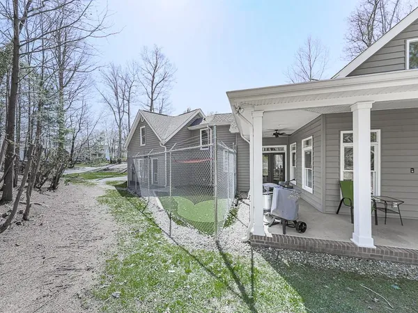 a view of a white house next to a yard with big trees