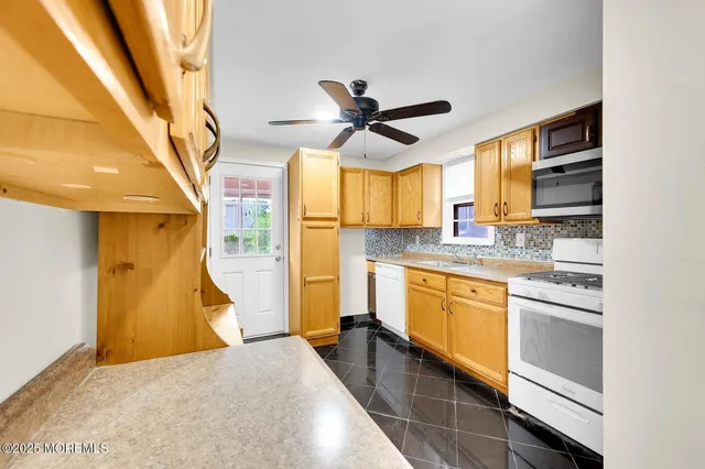 a kitchen with stainless steel appliances granite countertop a refrigerator a sink dishwasher a stove and white countertops with wooden floor