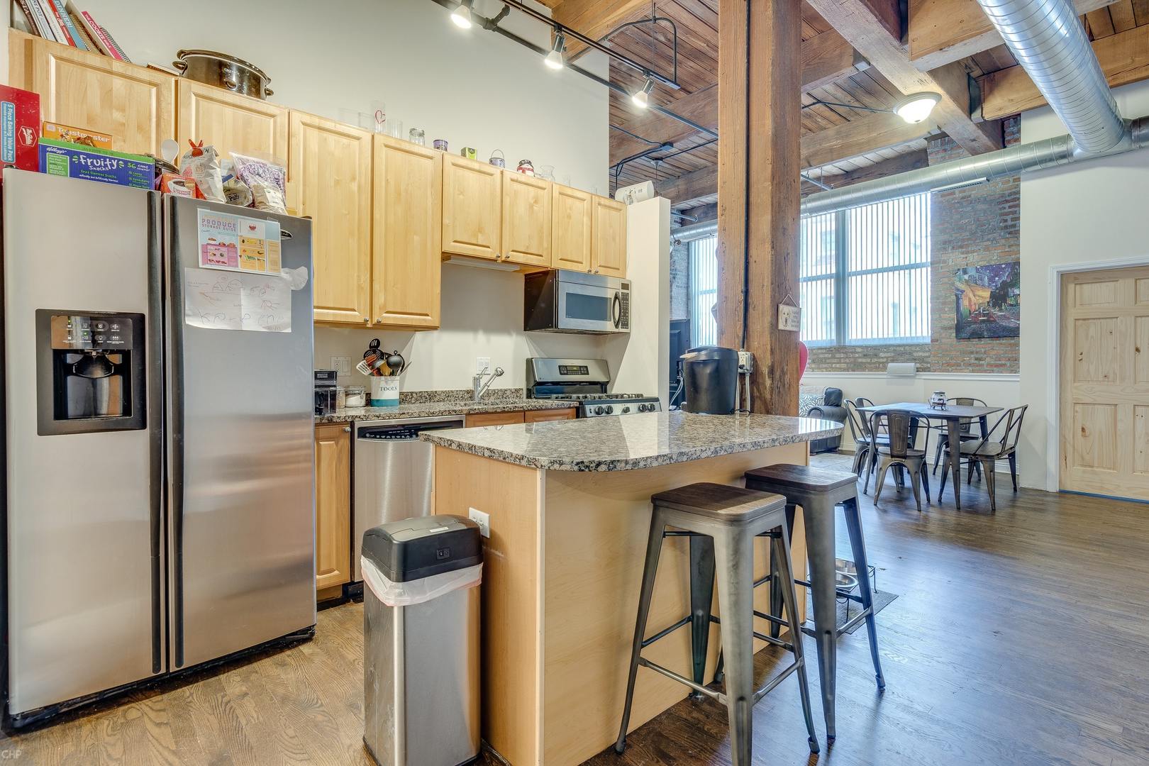 1500 West Monroe Street, Unit 122 Chicago, IL 60607 - Photo 4 of 14 a kitchen with stainless steel appliances granite countertop a stove a refrigerator a sink a dining table and chairs with wooden floor