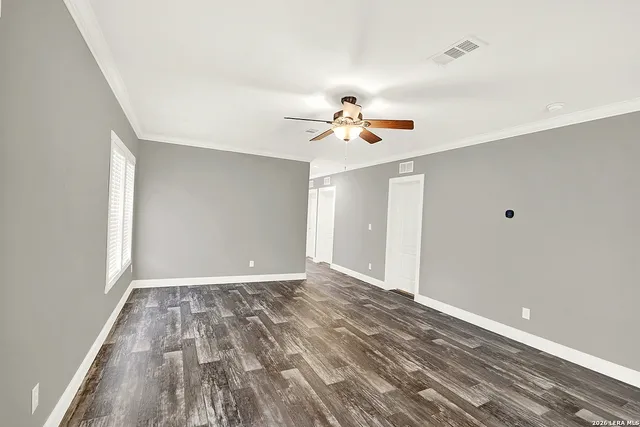 a view of empty room with wooden floor and fan
