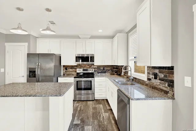 a kitchen with stainless steel appliances granite countertop a sink stove microwave and refrigerator