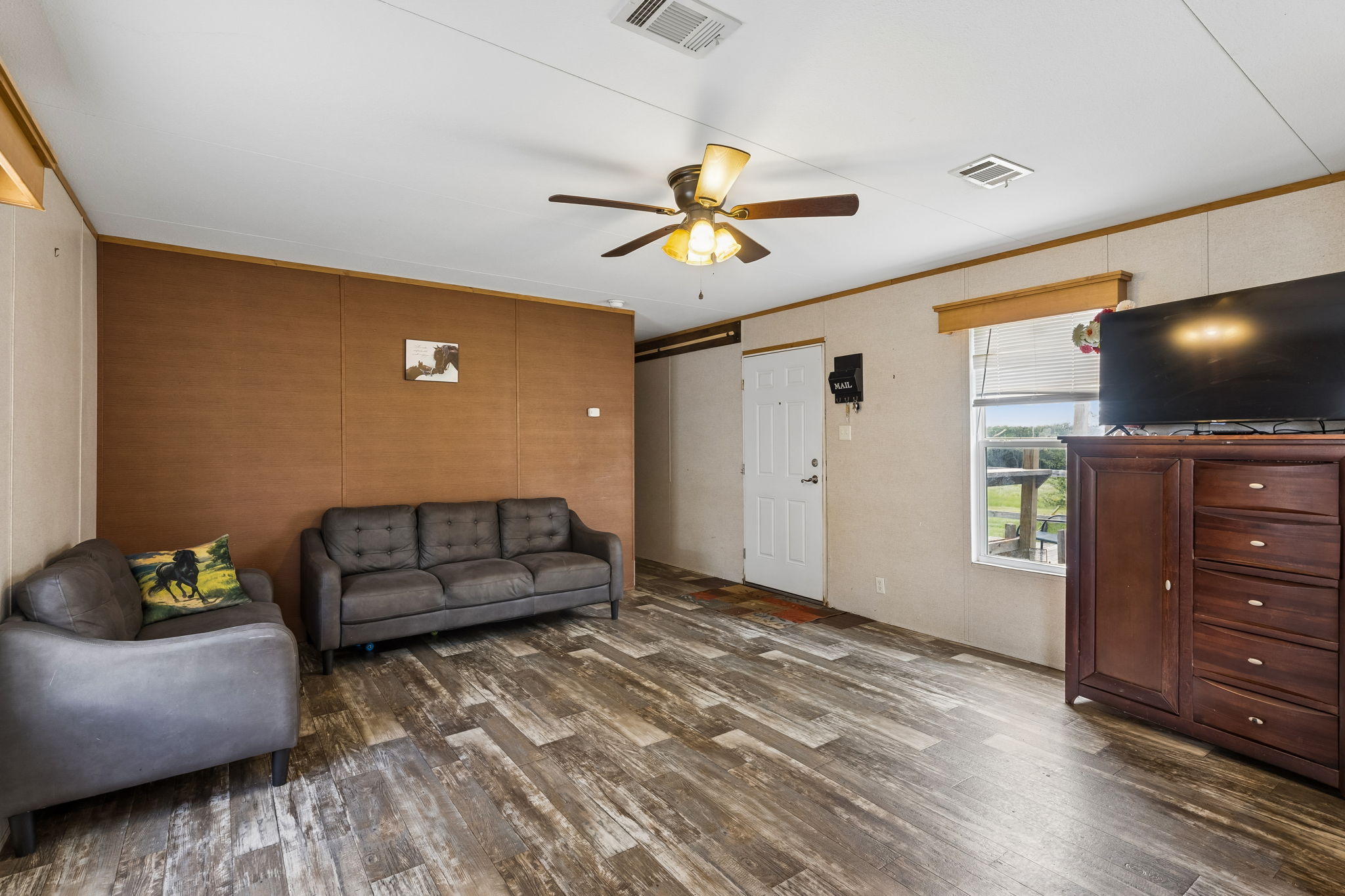 253 North County Line Road, Unit C Elgin, TX 78621 - Photo 9 of 39 A welcoming living room featuring textured wall panels and resilient wood-look flooring.