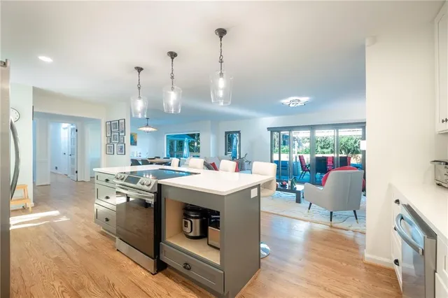 a view of kitchen with kitchen island stainless steel appliances wooden floor dining table and chairs