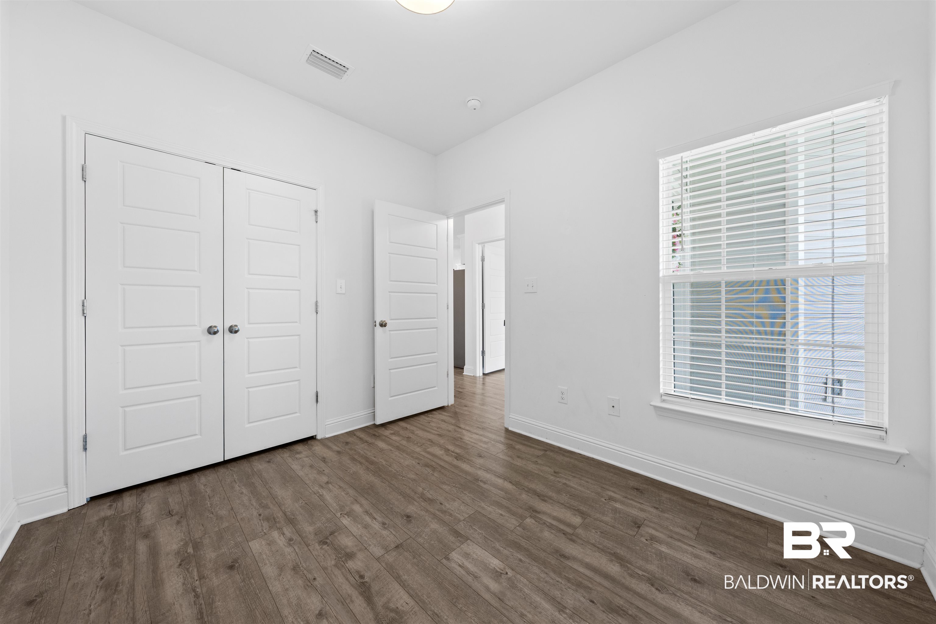2651 South Juniper Street, Unit 1801 Foley, AL 36535 - Photo 10 of 16 Spacious room featuring wood-finish flooring, white trim, and a large window with blinds