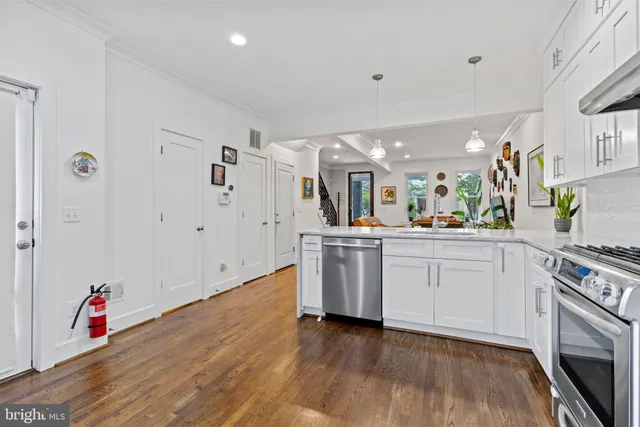 a kitchen with white cabinets and wooden floor