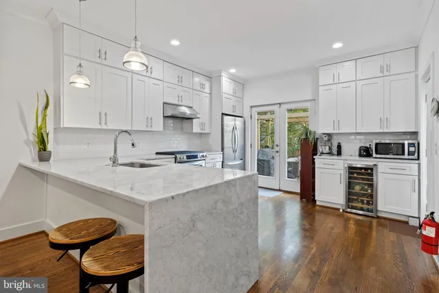 a kitchen with stainless steel appliances kitchen island granite countertop a sink a stove a refrigerator cabinets and a dining table with wooden floor