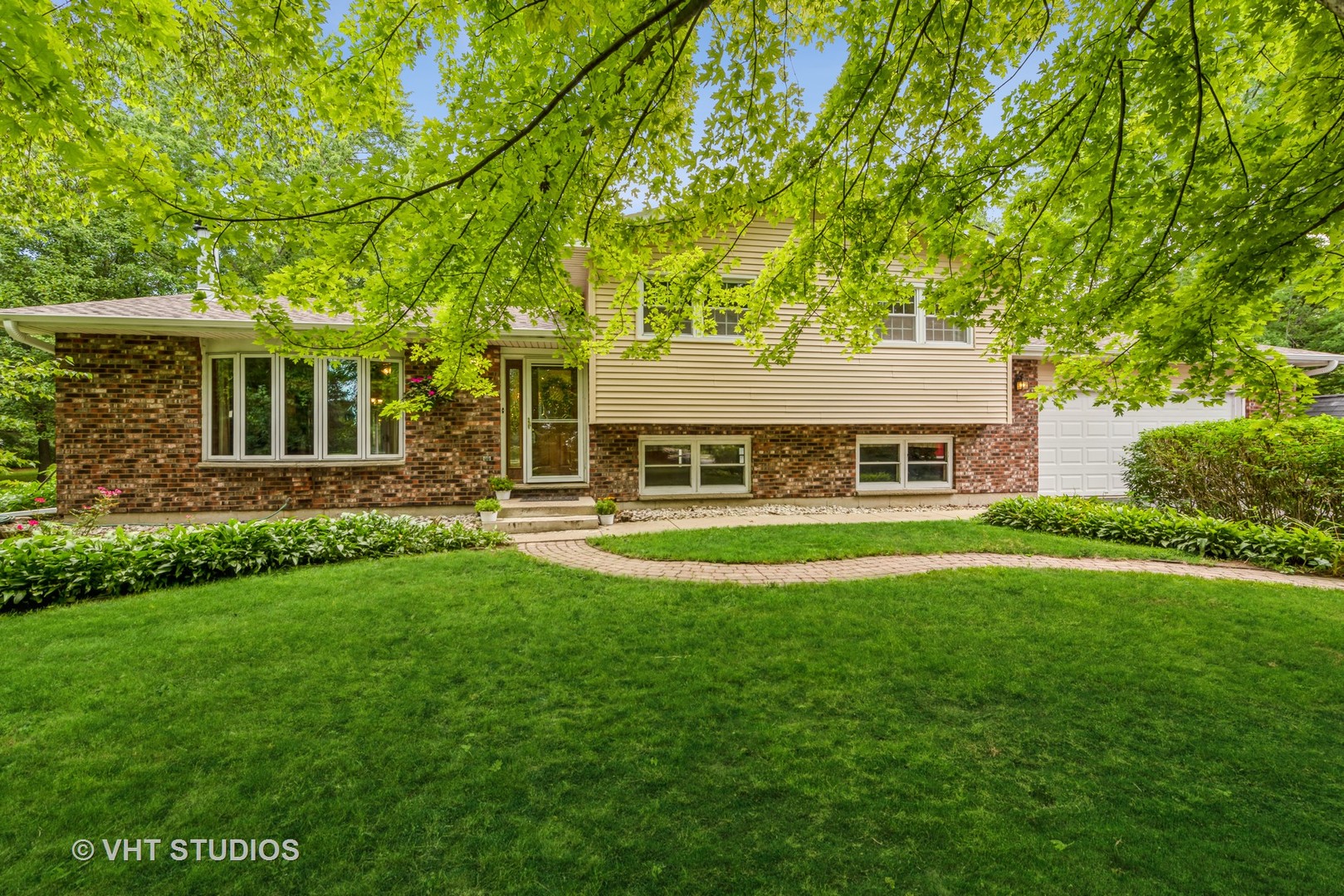 a view of a house with a big yard potted plants and large trees