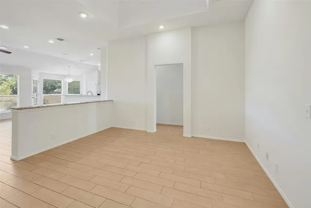 a view of empty room with wooden floor and kitchen