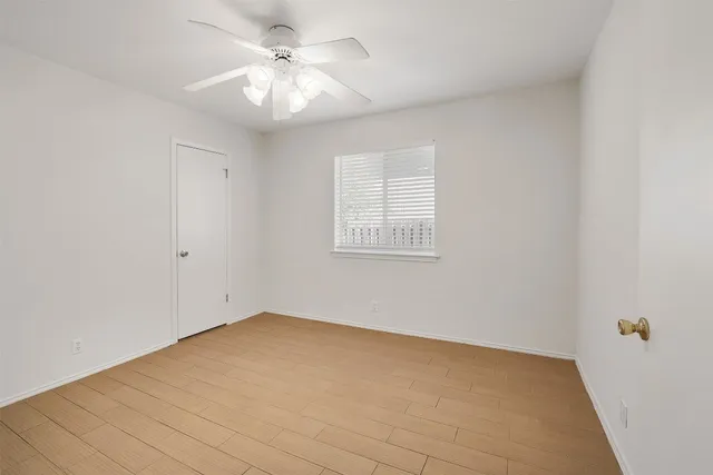 an empty room with windows and fan