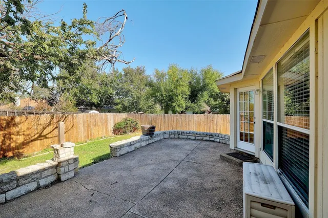 a view of backyard with large tree and wooden fence