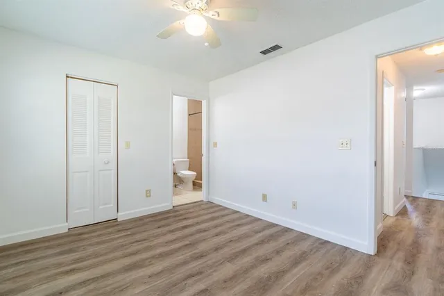 an empty room with wooden floor and chandelier fan