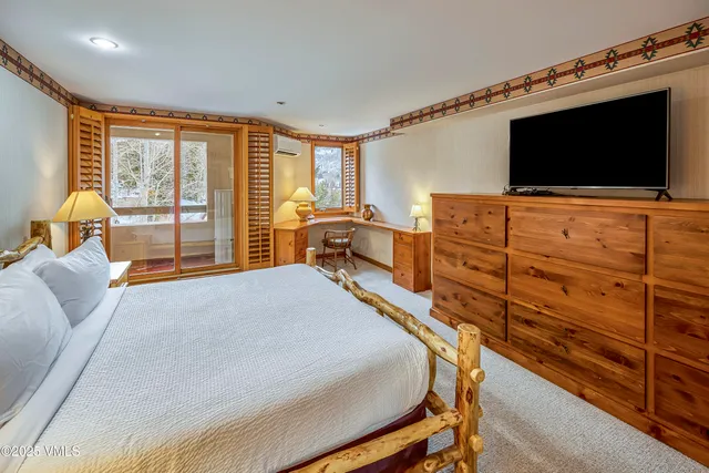 a bedroom with a bed and furniture with a flat tv screen