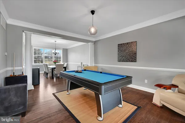 a room with furniture pool table wooden floor and windows