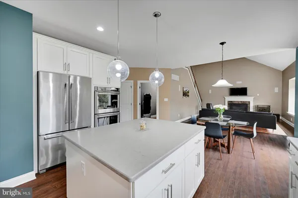 a large kitchen with kitchen island a refrigerator a stove a sink a dining table and chairs with wooden floor