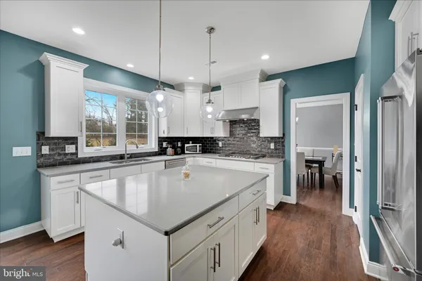 a large kitchen with kitchen island a large counter space a sink appliances and cabinets