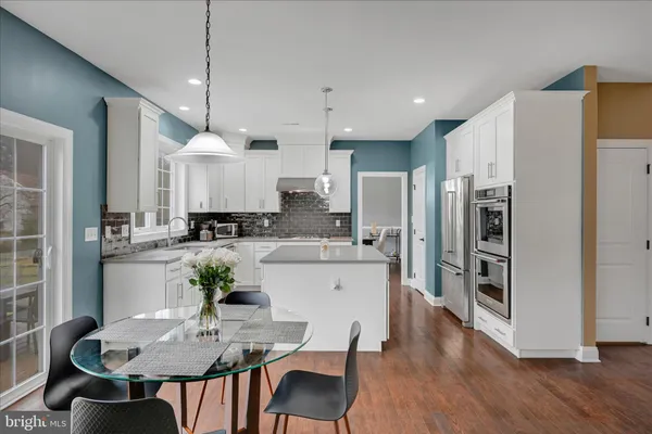 a kitchen with stainless steel appliances granite countertop a refrigerator a stove a sink a dining table and chairs