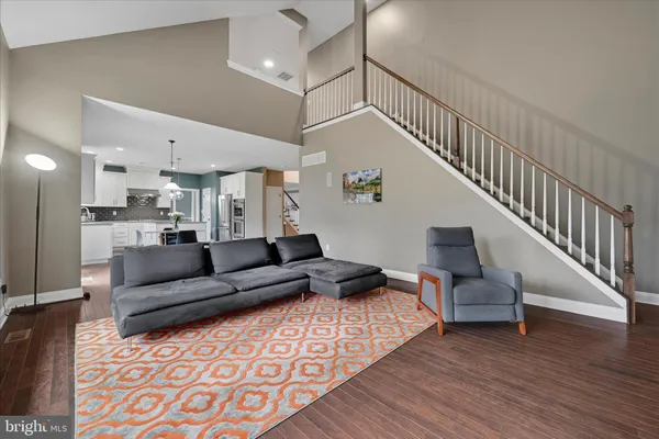 a living room with furniture and a dining table with wooden floor