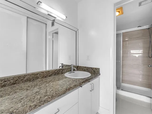 a bathroom with a granite countertop sink and a mirror