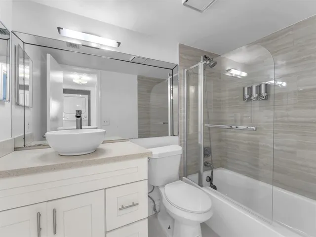 a bathroom with a toilet a sink a mirror a bathtub and shower