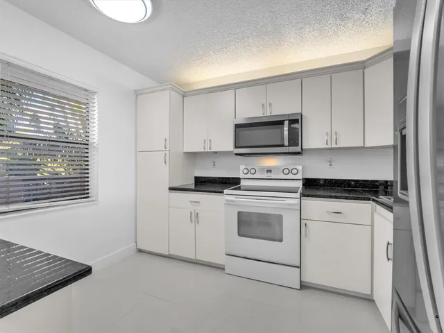 a kitchen with cabinets stainless steel appliances and a window