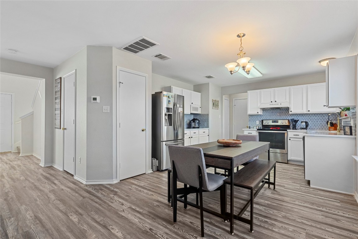 202 Rinehardt Street Hutto, TX 78634 - Photo 12 of 31 a view of a dining room with furniture a chandelier and wooden floor