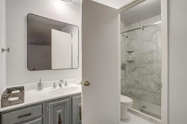 a bathroom with a granite countertop sink toilet and shower