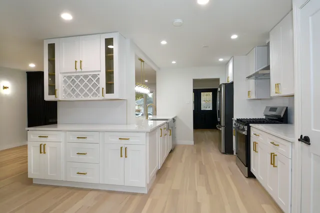 a kitchen with stainless steel appliances white cabinets sink and wooden floor
