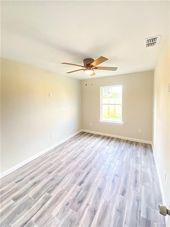 5048 McKenzie Road Brownsville, TX 78521 - Photo 7 of 11 an empty room with wooden floor fan and windows