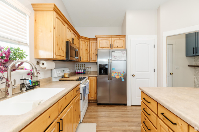 972 West 2840th Street South Logan, UT 84321 - Photo 9 of 46 Kitchen featuring natural wood cabinetry, light-toned countertops, a stainless steel refrigerator, white appliances, and wood-finish flooring