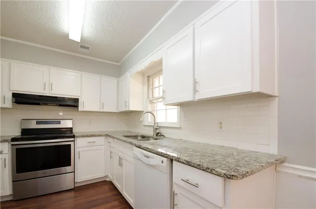 a kitchen with granite countertop white cabinets and stainless steel appliances