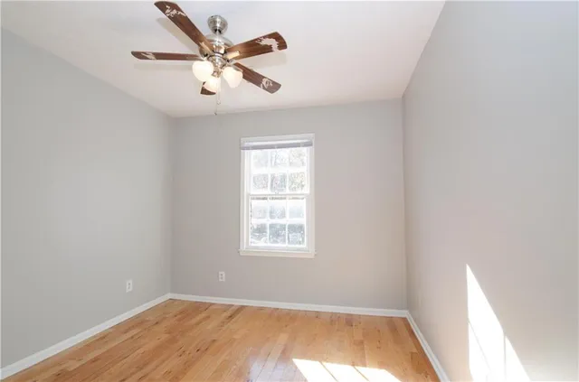 an empty room with wooden floor closet and windows
