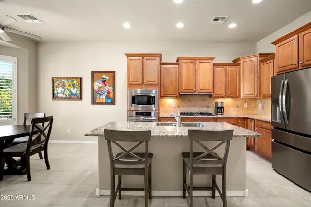 a kitchen with stainless steel appliances granite countertop a stove a refrigerator a oven a sink with a dining table and chairs