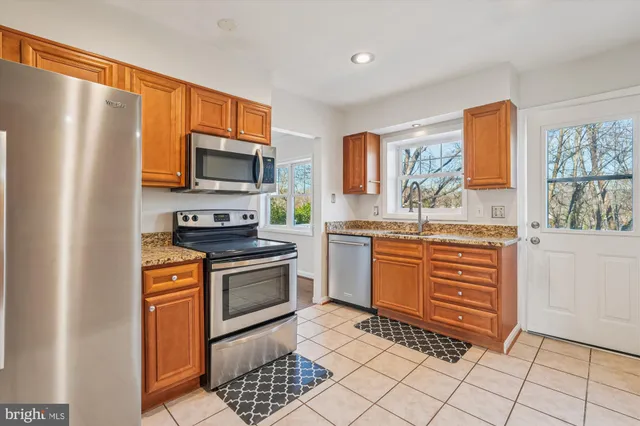 a kitchen with stainless steel appliances granite countertop a refrigerator a sink dishwasher and wooden floor