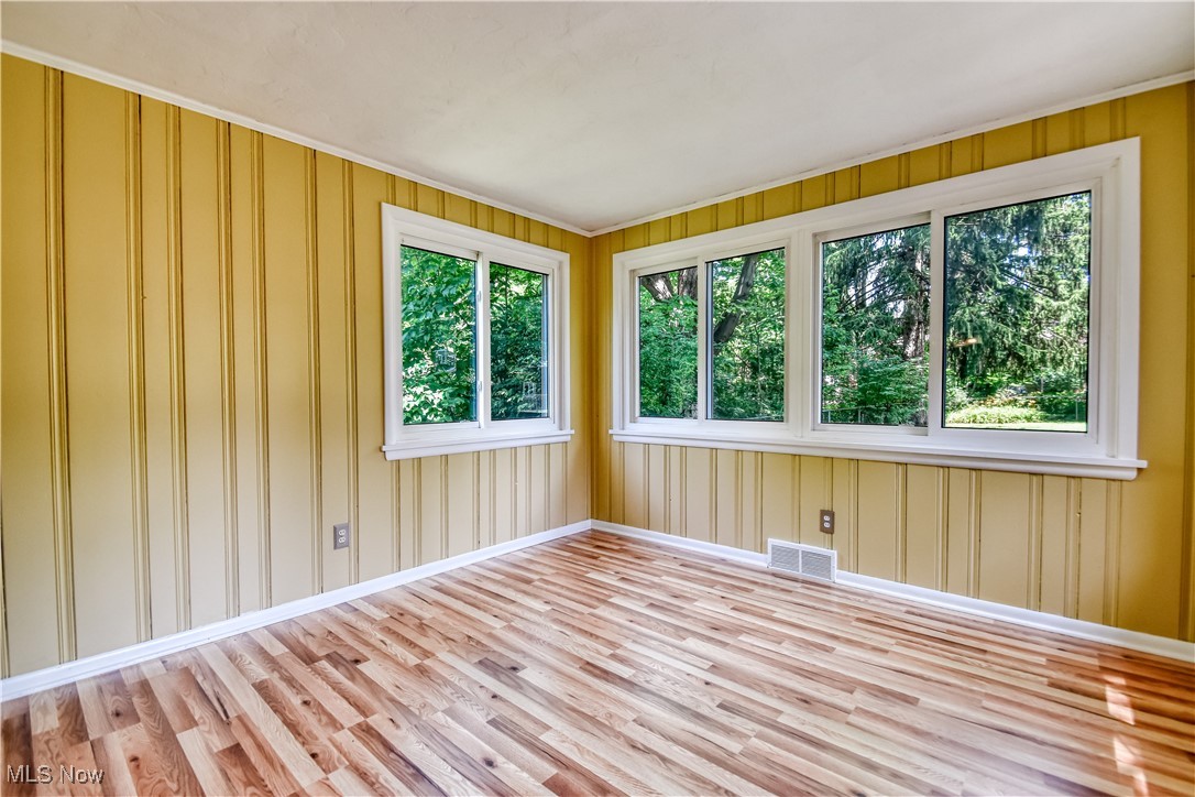 2607 Ashurst Road University Heights, OH 44118 - Photo 18 of 39 Empty room with wood finished floors, healthy amount of natural light, and ornamental molding