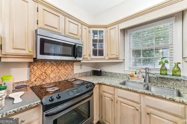 a kitchen with granite countertop a stove a sink and dishwasher wooden cabinets with granite countertops
