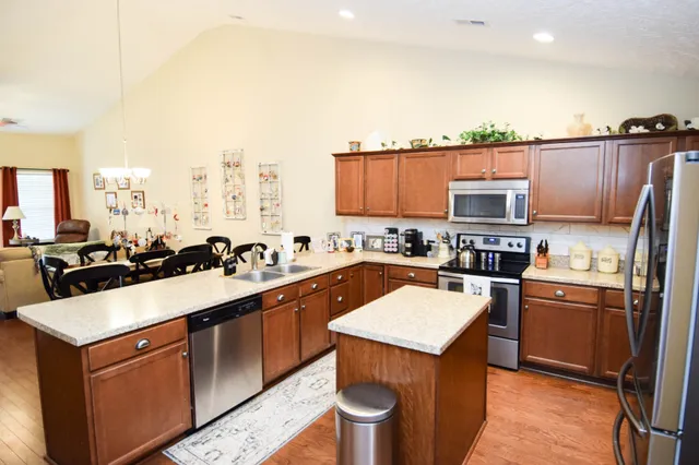 a kitchen with kitchen island granite countertop a sink a counter top space and cabinets
