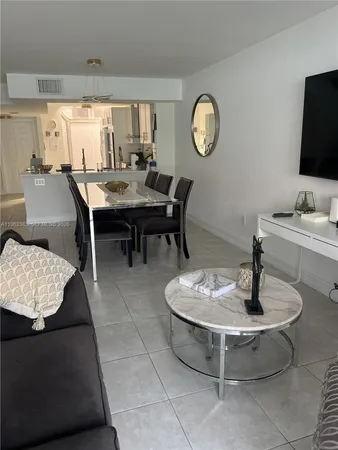 a living room with couches a fireplace and a dining table with wooden floor
