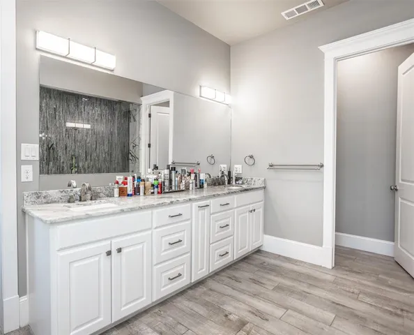 a bathroom with a granite countertop double vanity sink mirror and