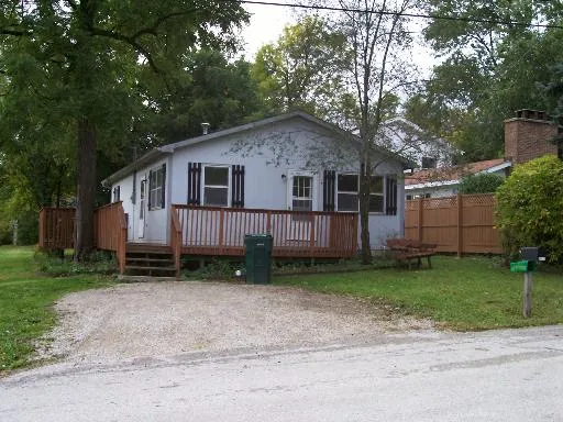 a view of a house with a yard plants and large tree
