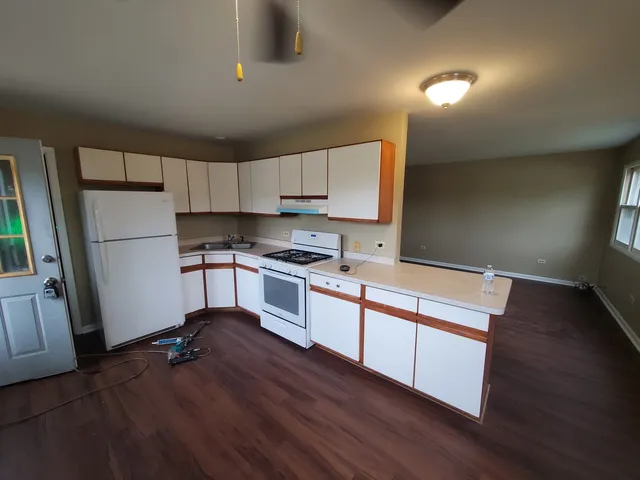 a kitchen with granite countertop a refrigerator stove and wooden floor