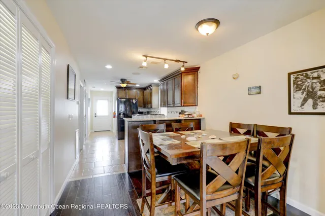 a kitchen with stainless steel appliances kitchen island granite countertop a dining table chairs and a refrigerator