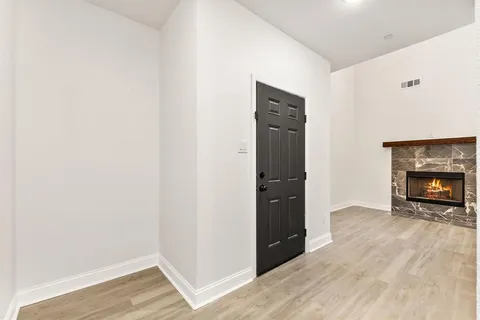 a view of an empty room with wooden floor and a fireplace