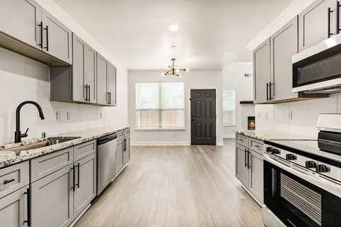 a kitchen with stainless steel appliances a sink dishwasher a stove and a microwave oven with wooden floor