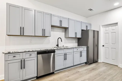 a kitchen with stainless steel appliances granite countertop white cabinets sink and refrigerator