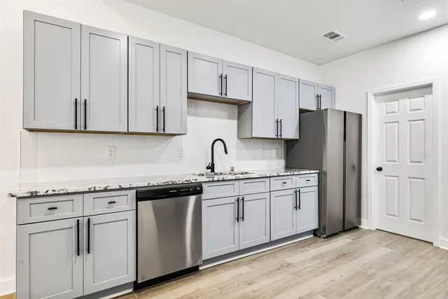 a kitchen with stainless steel appliances granite countertop white cabinets sink and refrigerator