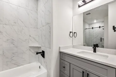 a bathroom with a sink and mirror with bathtub
