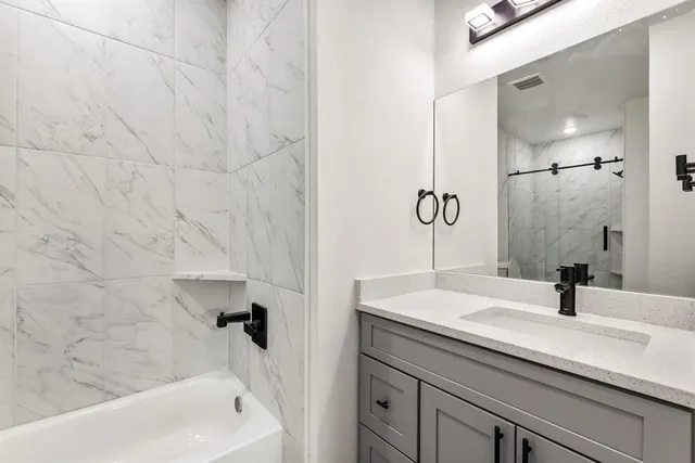 a bathroom with a sink and mirror with bathtub